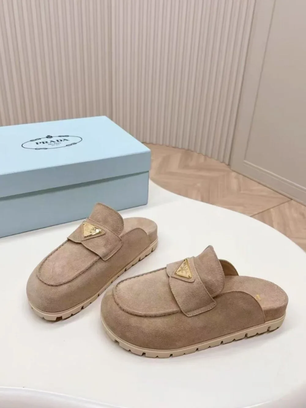 Prada beige slip‑on mules with triangular logo badge
